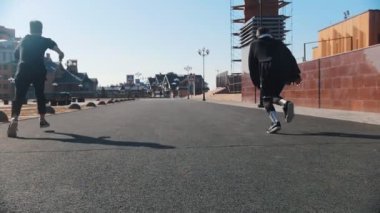 Şehir sokakları. Sokakta koşan ve numara lar yapan iki adam.