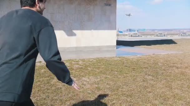 Un joven realizando trucos acrobáticos y volteretas en la hierba — Vídeo de stock
