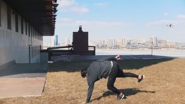 Um jovem realizando truques acrobáticos na grama — Vídeo de Stock