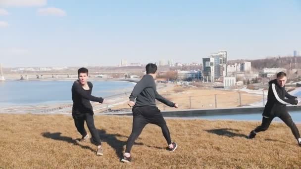 Τρεις νεαροί άνδρες κάνουν ακροβατικά κόλπα στο γρασίδι — Αρχείο Βίντεο