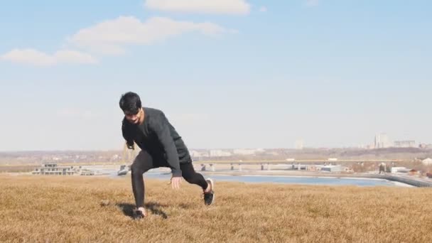 En man i svarta kläder utför akrobatiska tricks på gräset — Stockvideo