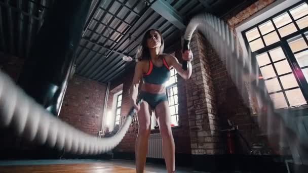 Uma mulher a fazer crossfit no ginásio. Treinando suas mãos com cordas batendo no chão — Vídeo de Stock