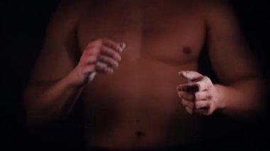 Atletik gömleksiz bir adam bir talk ile ellerini çırparak ve mücadele poz ayakta