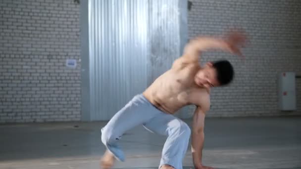 Um homem acrobático sem camisa a treinar as suas habilidades. Mostrando elementos de capoeira — Vídeo de Stock