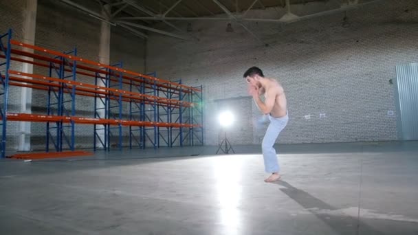 Um homem acrobático sem camisa a treinar as suas habilidades. Mostrando elementos de capoeira. Executando um pontapé de ar — Vídeo de Stock