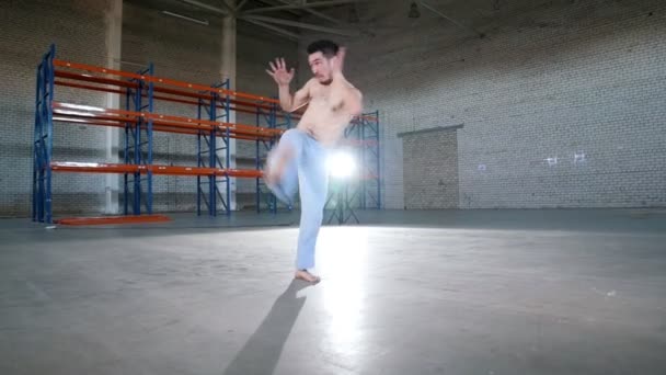 Un hombre acrobático entrenando sus habilidades. Mostrando elementos de capoeira. Realizar una patada de aire — Vídeo de stock