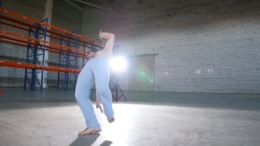 Aydınlık bir oda. Bir atletik adam onun capoeira becerilerini eğitim ve farklı flips performans