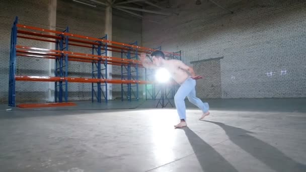 Una stanza luminosa. Un uomo atletico che allena le sue abilità da capoeira . — Video Stock