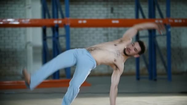 Una habitación luminosa. Un atlético entrenando sus habilidades de capoeira y saltando sobre sus manos — Vídeos de Stock