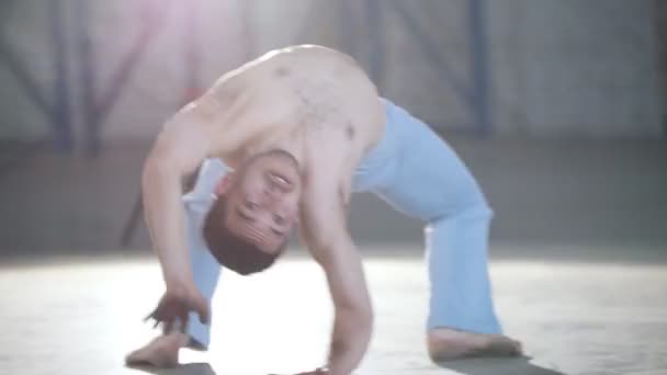Un hombre sin camisa entrenando sus habilidades. Mostrando elementos de capoeira — Vídeos de Stock