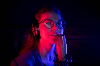Neon Aydınlatma mikrofon tarafından şarkı gözlük genç güzel bir kadın