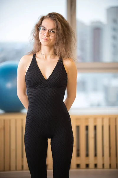 Giovane bella donna in occhiali in piedi nella sala fitness — Foto Stock