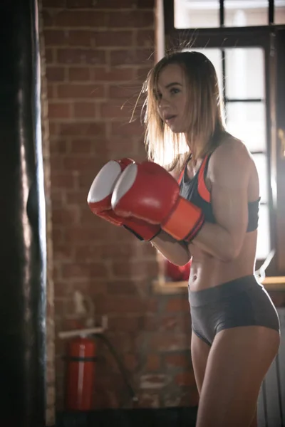 Una atlética con guantes de boxeador de pie en el gimnasio —  Fotos de Stock