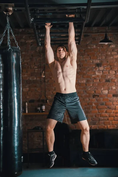 천장 사다리를 사용하여 손을 앞으로 이동하는 운동 선수 남자 — 스톡 사진