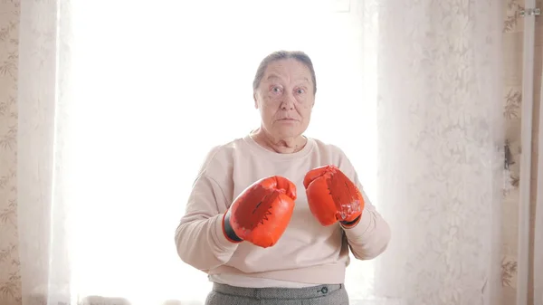 An old woman in boxing gloves is ready to fight