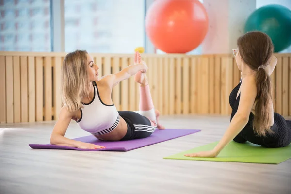 Két fiatal nő csinál jóga a fitneszstúdióban. Gyakorlatok a gerinc — Stock Fotó