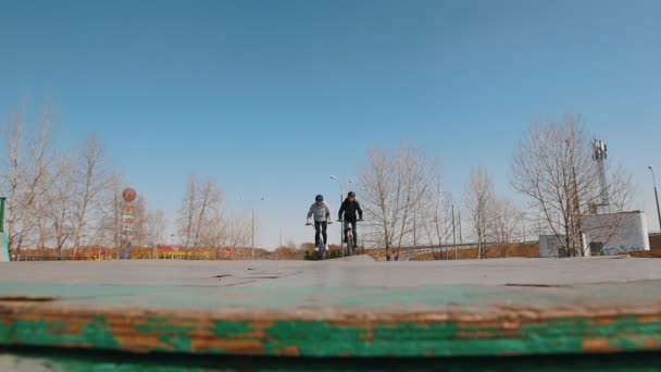 Twee mannen op fietsen rijden in het Skatepark uitvoeren truc. — Stockvideo