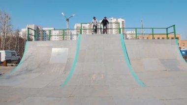 İki adam Bmx biniciler kaykay parkta yokuş aşağı gidiyor