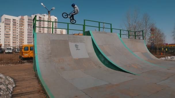 Un coureur de bmx seul en sweat à capuche gris sur les rampes du skatepark — Video