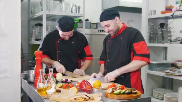 Cocina del restaurante. Dos hombres trabajando en servir platos cortando verduras — Vídeo de stock