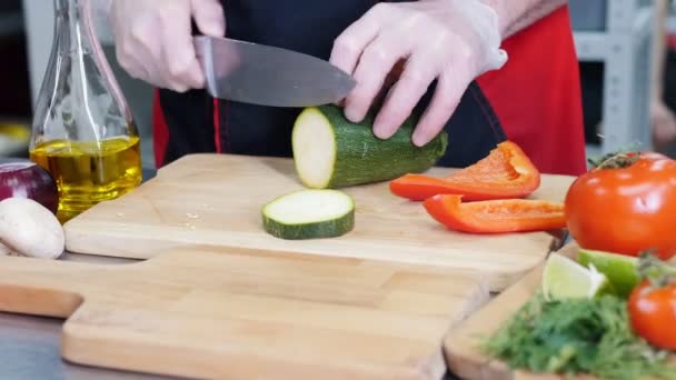 Un chef trabajando en la cocina. Cortar un calabacín verde — Vídeos de Stock