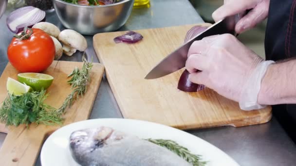 Un chef trabajando en la cocina. Cortar una cebolla . — Vídeo de stock