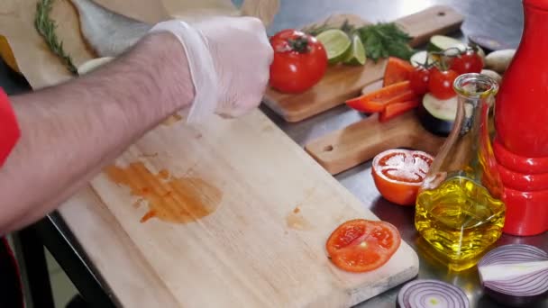 Un chef en la cocina del restaurante cortado tomate y limón para el relleno de pescado — Vídeo de stock