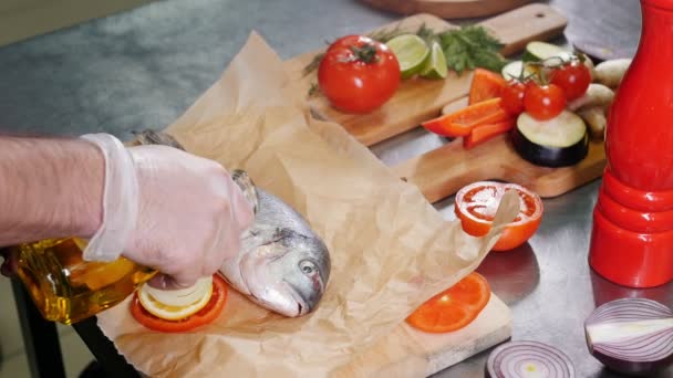 Un chef trabajando en la cocina. Engrasar el pescado con un aceite — Vídeo de stock