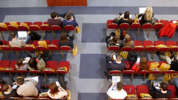 Una formación de negocios en el pasillo. La gente está sentada en sillones rojos y esperando que empiece el entrenamiento. — Vídeos de Stock