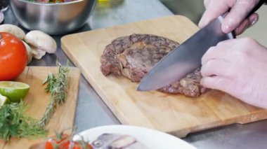 Mutfakta çalışan bir şef. Kızarmış biftek kesen bir şef