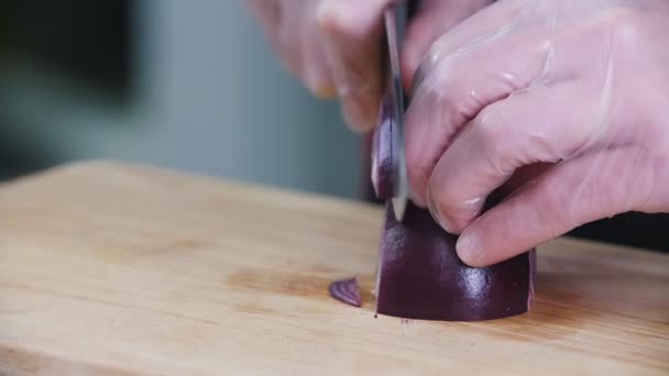 Een chef-kok die in de keuken werkt. Een rode ui snijden. — Stockvideo