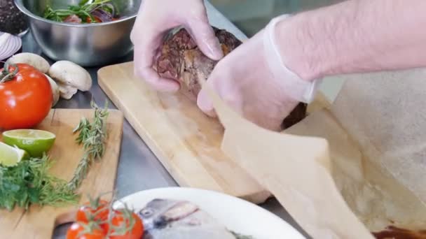 Ένας σεφ που δουλεύει στην κουζίνα. Ο σεφ βάζει μια τηγανιτή μπριζόλα σε μια σανίδα κοπής. — Αρχείο Βίντεο