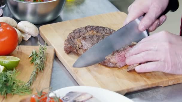 Cozinha de restaurante. Um chef cortando bife frito — Vídeo de Stock