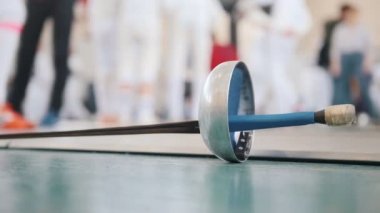 Eskrim turnuvası. Katılımcılar düello yaparken yerde yatan bir kılıç