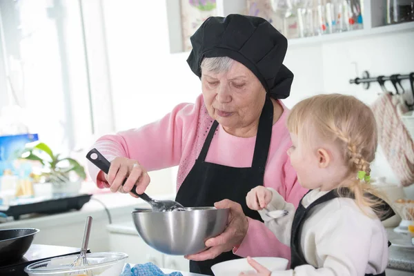 Familia en la cocina. Una abuela sosteniendo un tazón — Foto de Stock