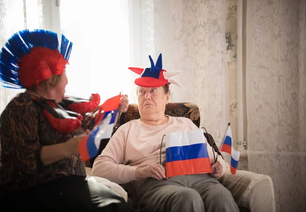Две пожилые женщины, сидящие в российских аксессуарах с российскими флагами — стоковое фото