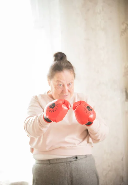 An old woman in red boxing gloves is ready to fight