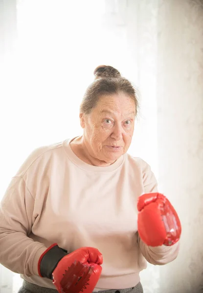 An old woman in boxing gloves looking in the camera