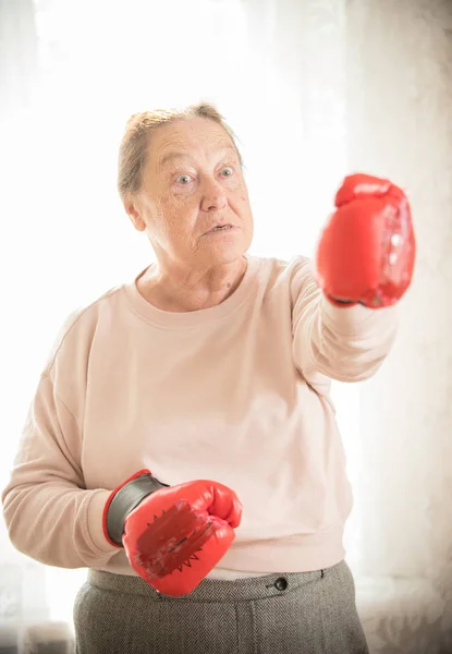 An angry old woman standing in boxing gloves