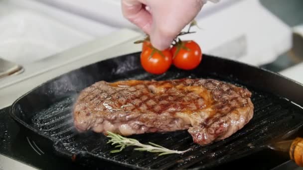 Restaurant keuken. Chef Frituur stuk steak en zet cherry tomaten in de pan — Stockvideo