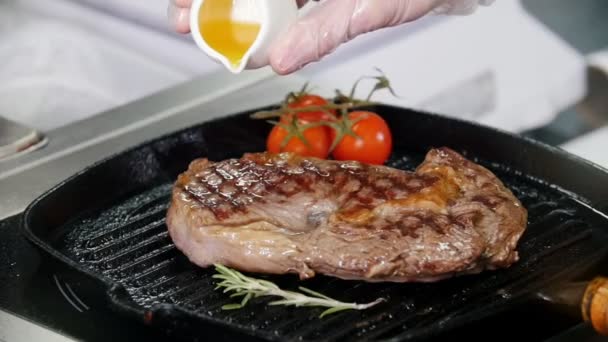 Étterem konyha. Chef sütés darab steak a serpenyőben. Hozzáadása gyümölcslé tetejére — Stock videók