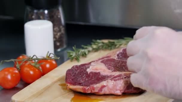 Restaurant kitchen. Chef preparing the meat. Pouring an oil on it — Stock Video