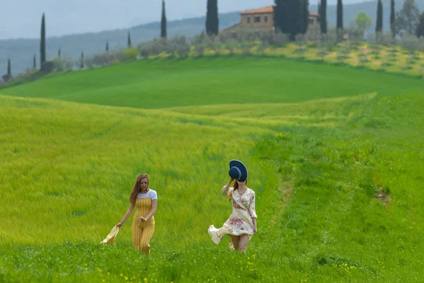 Zwei glückliche Frauen, die auf einer hellgrünen Wiese spazieren gehen — Stockfoto