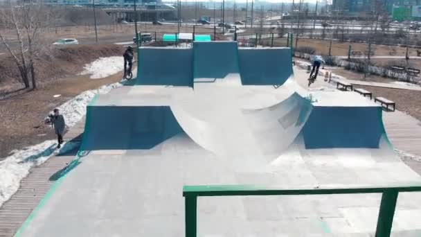 Vista aérea de un parque de skate. Dos jinetes profesionales BMX para hombres montando en las rampas — Vídeo de stock