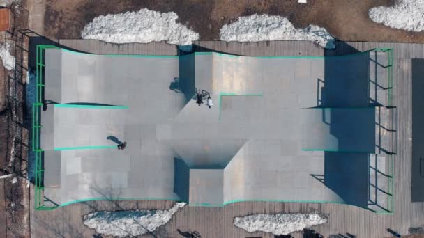 Vue aérienne sur un skatepark. Cavaliers professionnels BMX sur les rampes d'un petit skatepark — Video