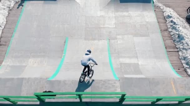 Vista aérea de un parque de skate. BMX rider va cuesta abajo desde la rampa — Vídeo de stock