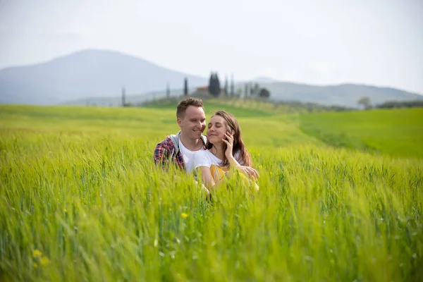 Молодая счастливая пара сидит на зеленом лугу — стоковое фото