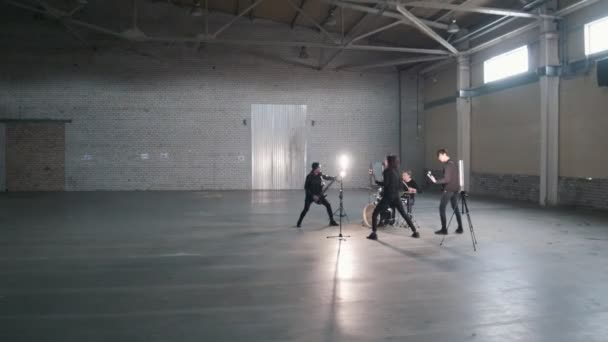 Un grupo joven tocando música rock en un hangar — Vídeo de stock