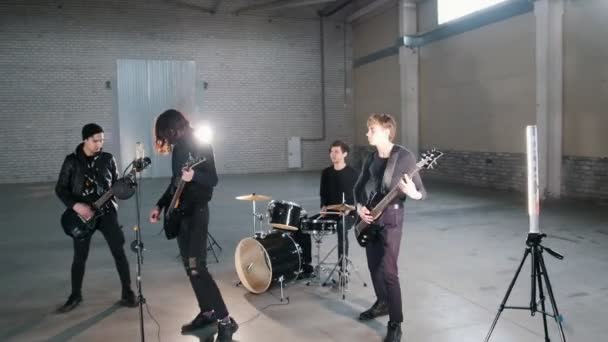 Um grupo jovem tocando música rock em um hargar — Vídeo de Stock