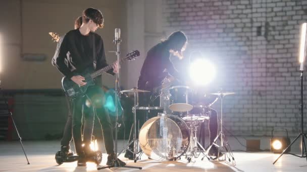 Une répétition. Un jeune groupe de personnes jouant de la musique rock dans un hargar lumineux — Video